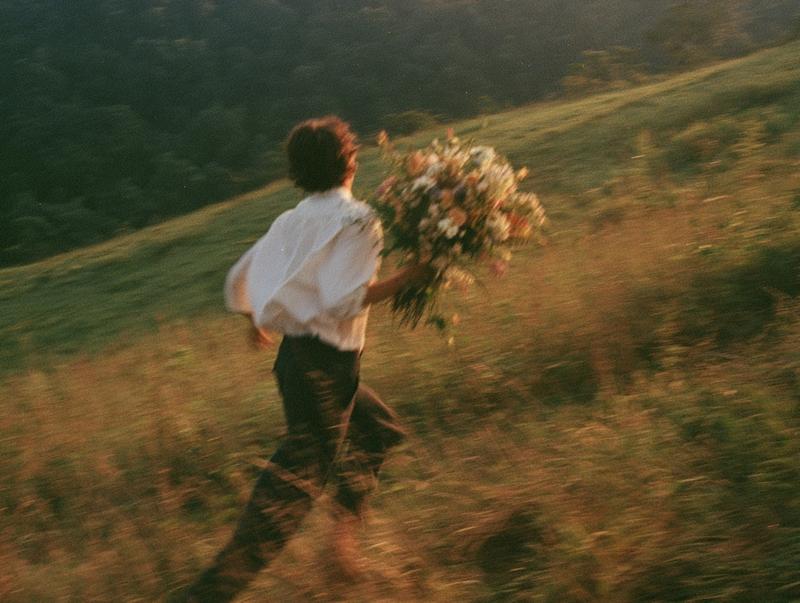 A solitary figure runs across a sunlit hillside carrying...