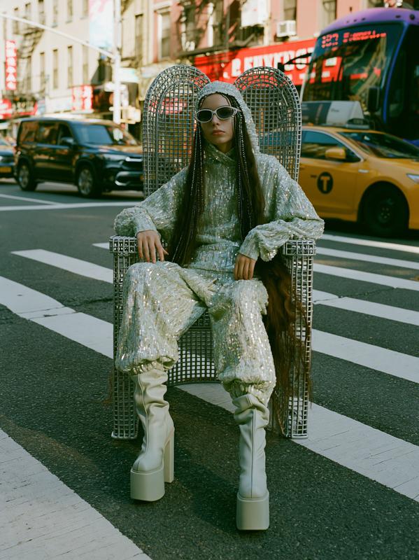 A fashionista sits on a queen-like metal chair on...